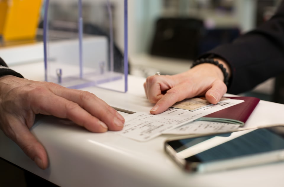 Boarding pass and passport on a table with hands on top of the documents