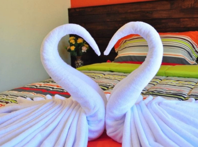 Charmante Nahaufnahme von zwei Handtüchern auf einem Hotelbett, kreativ in Form von Schwänen arrangiert.