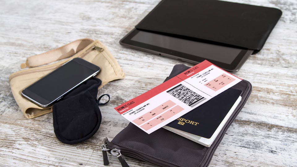  Travel flat lay: phone, sleeping mask, tablet, passport, and business class ticket on wood. Ready for a trip!