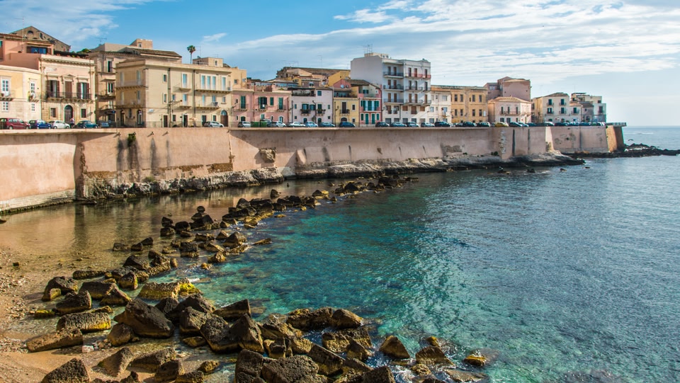 un'immagine di edifici dietro un muro vicino al mare