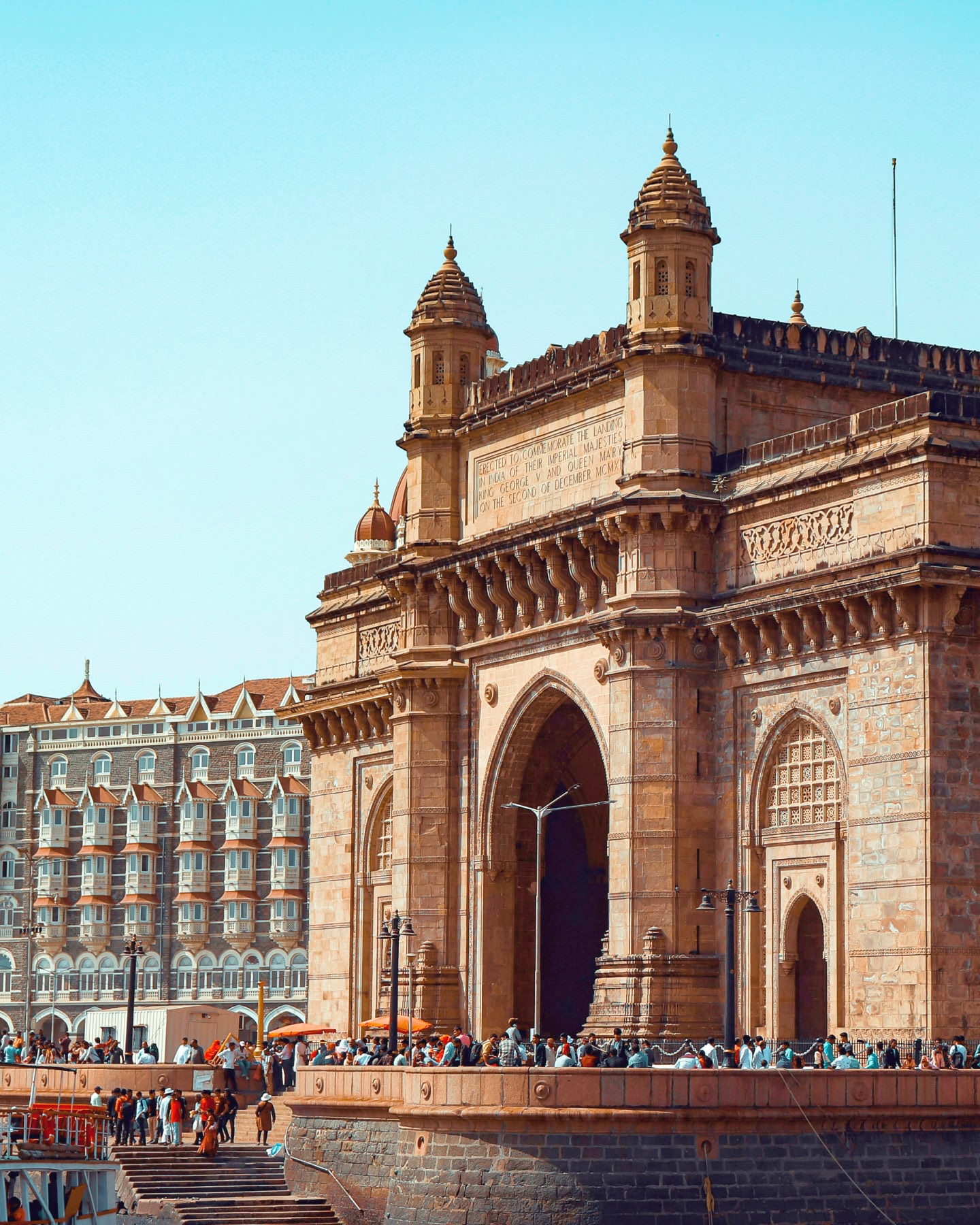 Gateway of India in Mumbai with crowds gathered at its base.