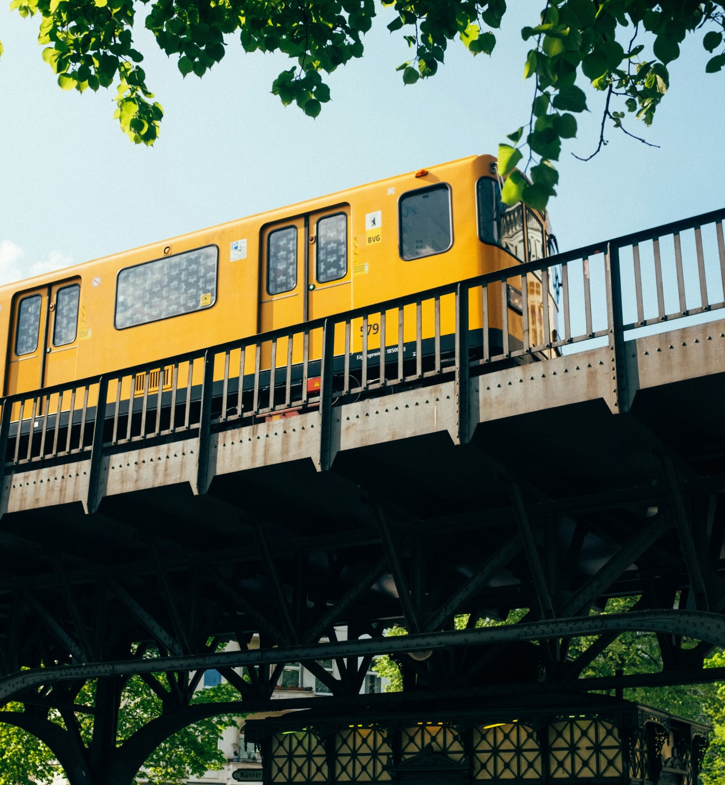 Un métro jaune vif traverse un pont surélevé en acier à Berlin, en Allemagne.