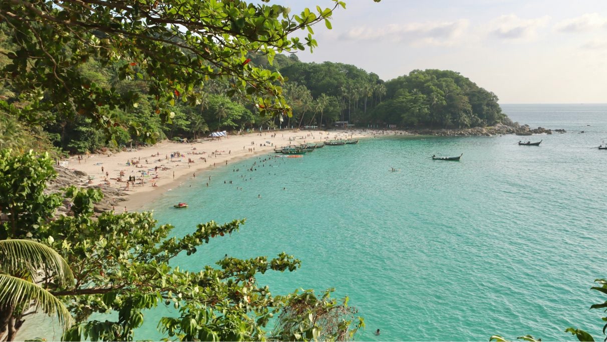 An image of the beach and light blue water with many people and boats during daytime. 