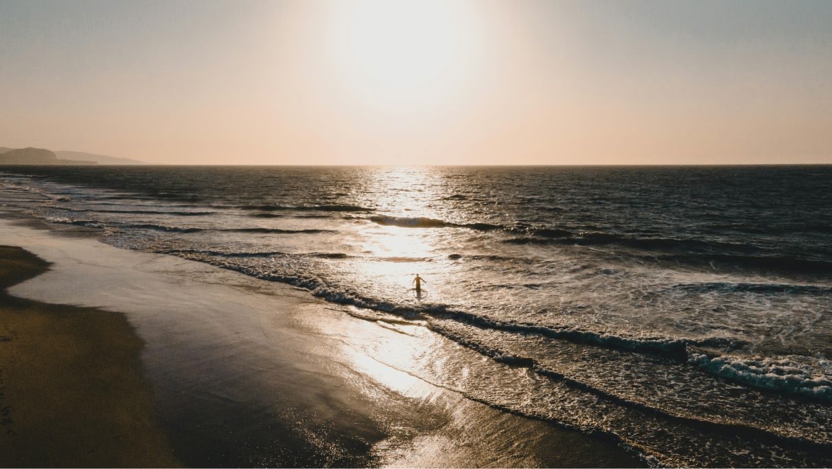 An image of the sea waves crashing on the seashore during sunset.