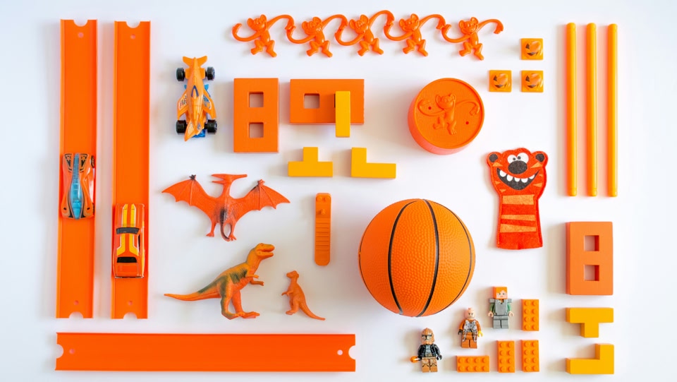a selection of orange children's toys arranged on a white background
