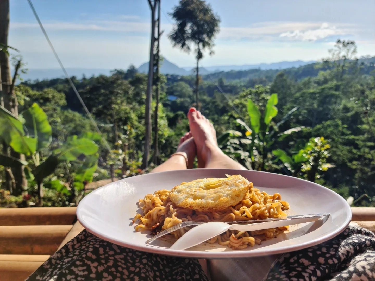 A female traveler enjoying the view of mountains and palm trees while holding self-cooked food