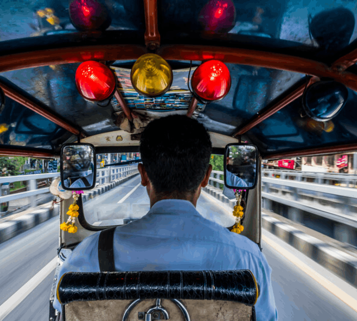 Immersive point-of-view shot from inside a tuk-tuk, offering a glimpse of the driver in control at the front, navigating the open road ahead
