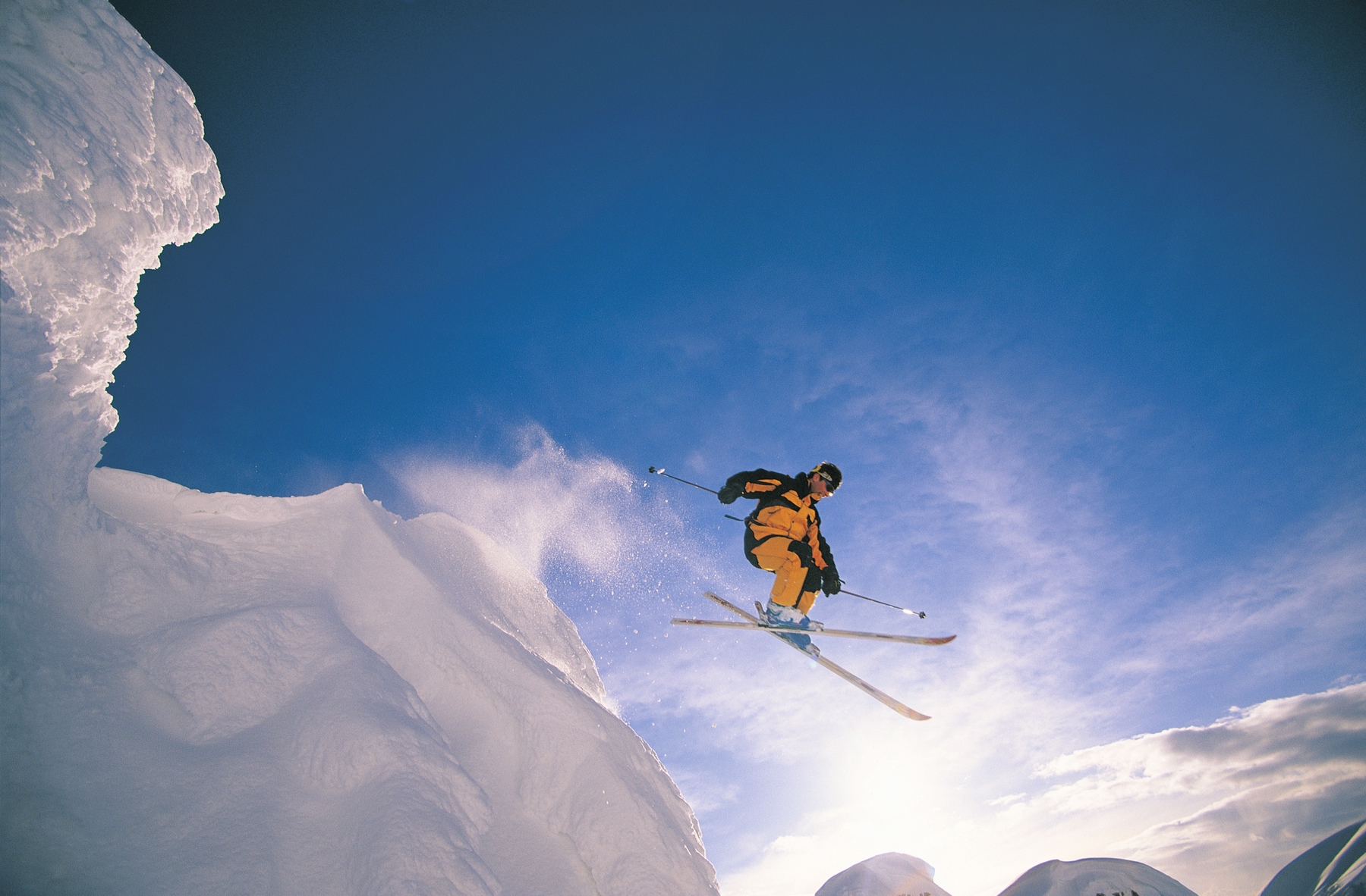 A skier floats mid-air as they have just passed an elevated ledge.