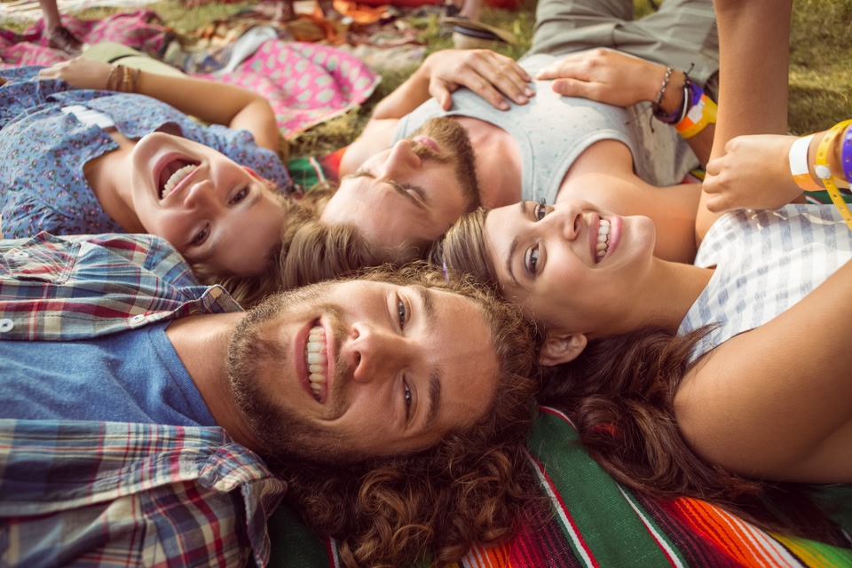 group of friends resting on a blanket on the ground in summer