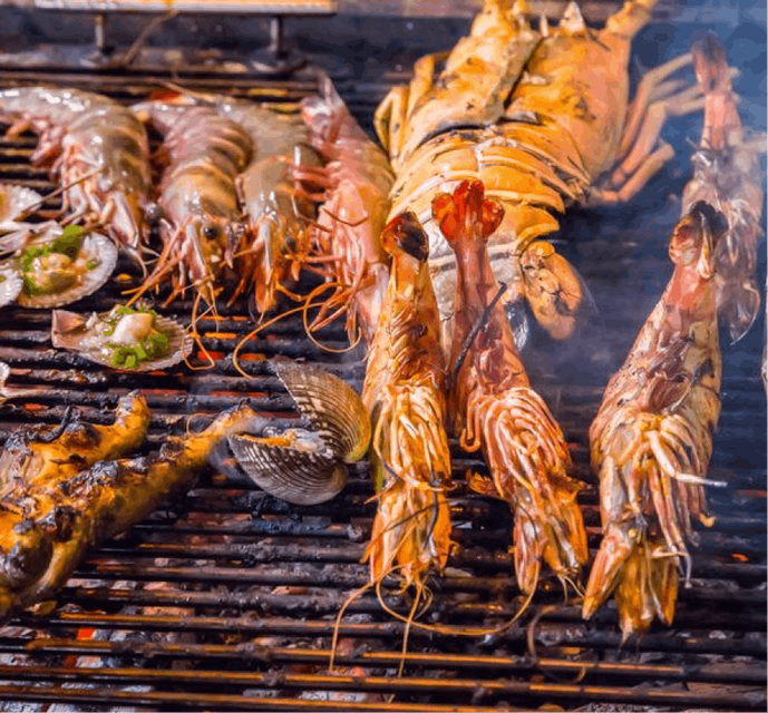 A close up shot of a lot of seafood, including prawns and clams being fired on a BBQ.