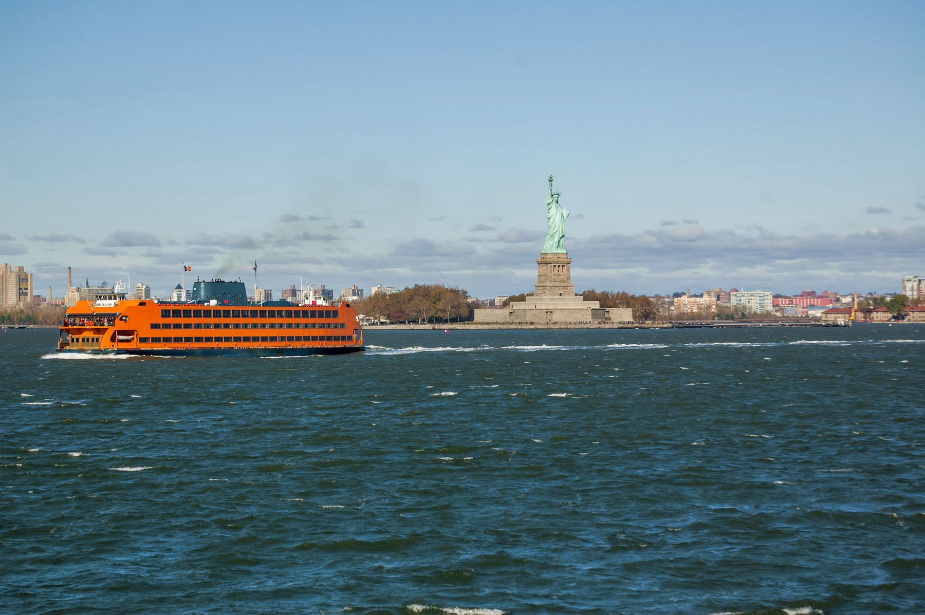 Orange Staten Island Ferry in front of the Statue of Liberty