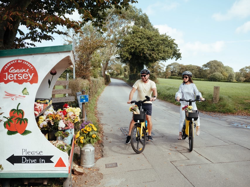 Couple on bikes stopping to look at a flower stall in Jersey