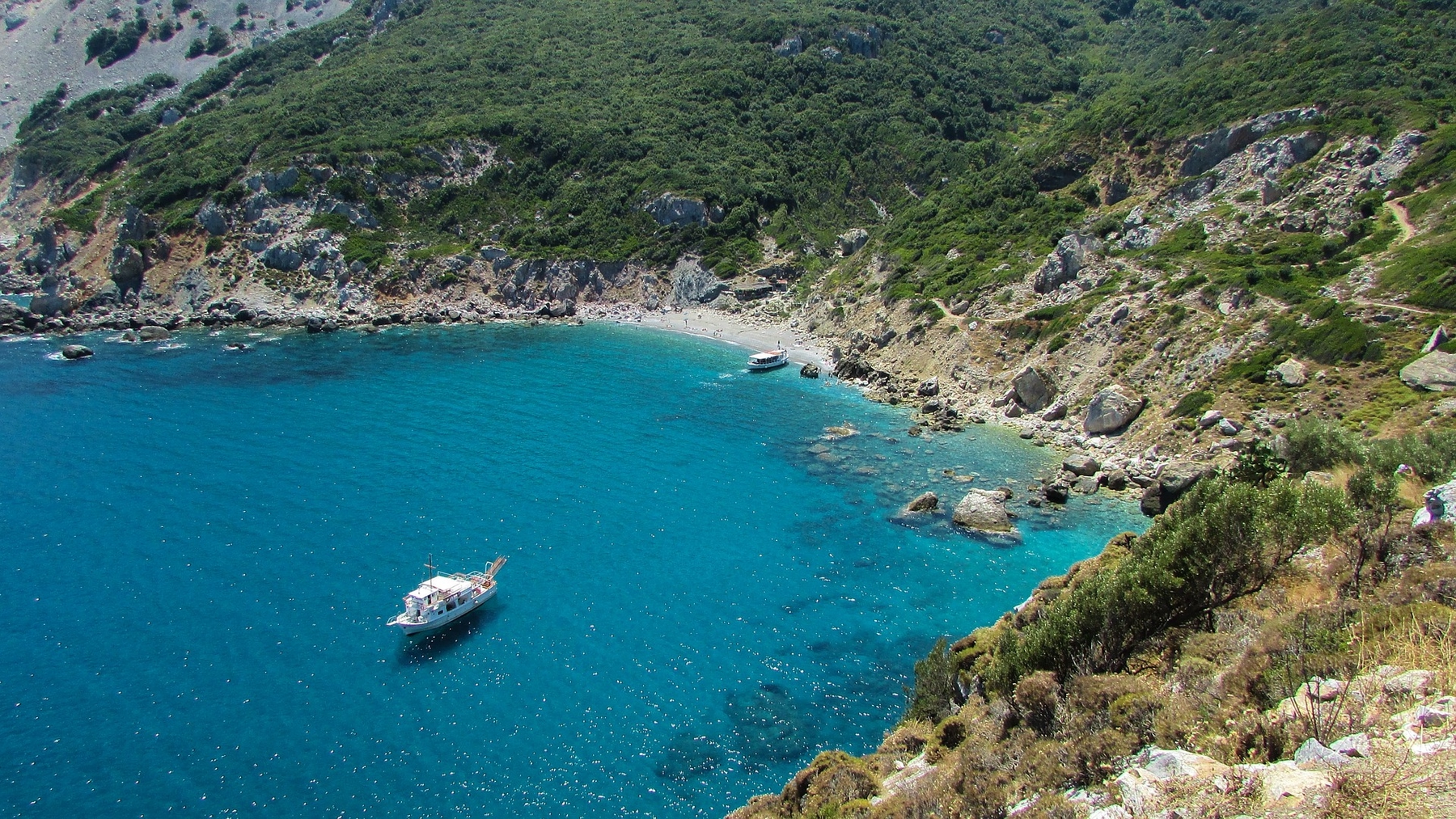 A boat approaches an island cove in Greece, where Americans can find international flight deals to.