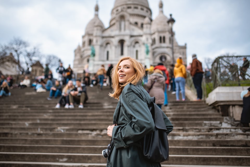Mulher em frente à Sacre Coeur sorrindo - skyscanner é confiável