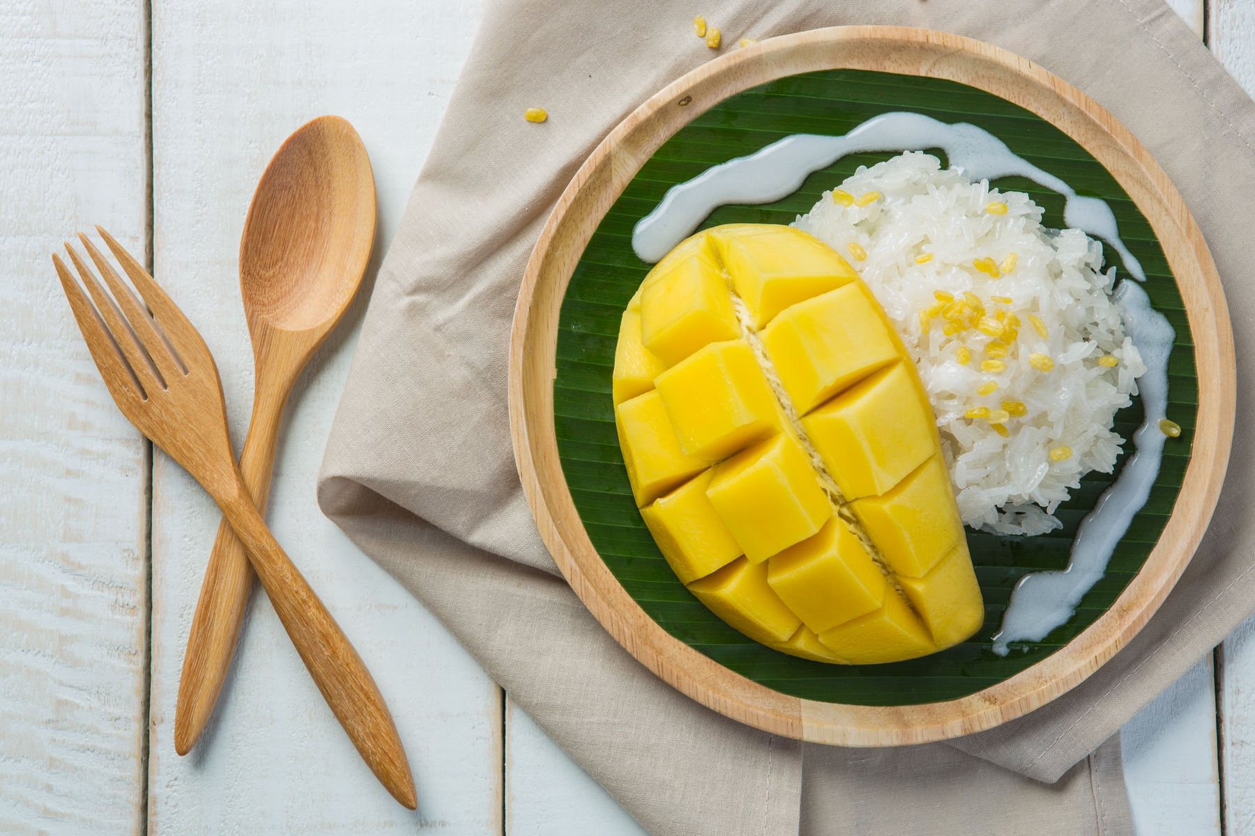 plate of mango sticky rice with wooden cutlery