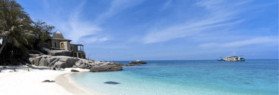 A wide angle shot of Bac My An beach showing its white sands, blue sea and a boat out in the water.