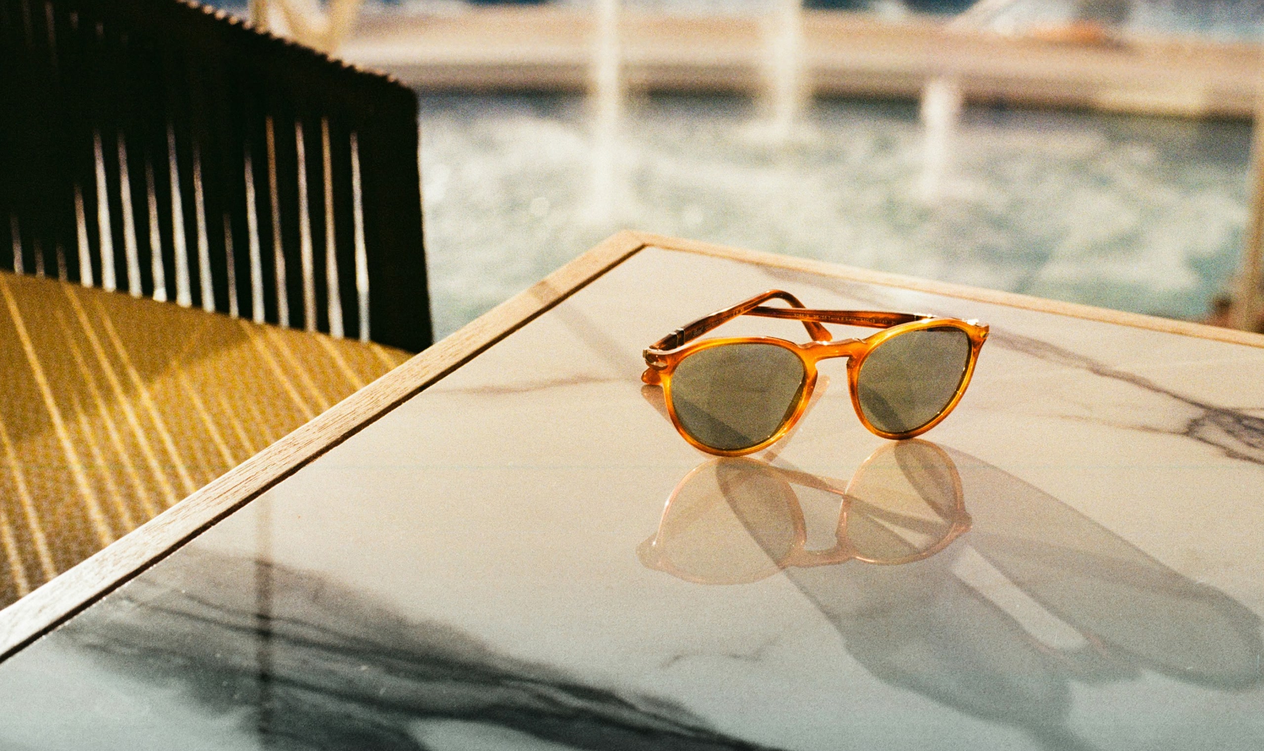 プールサイドの大理石天板のテーブル上に置かれたべっ甲柄のサングラス。