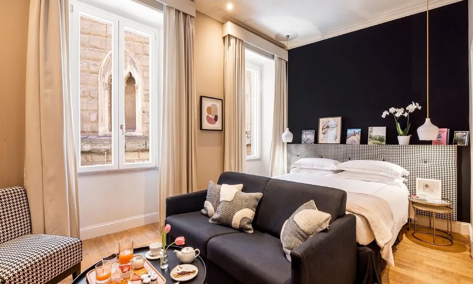 Habitación del Hotel Boutique Nerva de Roma. La mesa situada en la zona de descanso al final de la cama tiene una bandeja con artículos de desayuno.