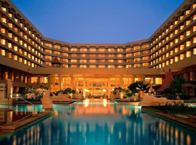 Stunning view of the JW Marriott Mumbai Juhu hotel's pool area at night, with the sparkling water and surrounding palm trees beautifully illuminated, creating a luxurious and tranquil ambiance