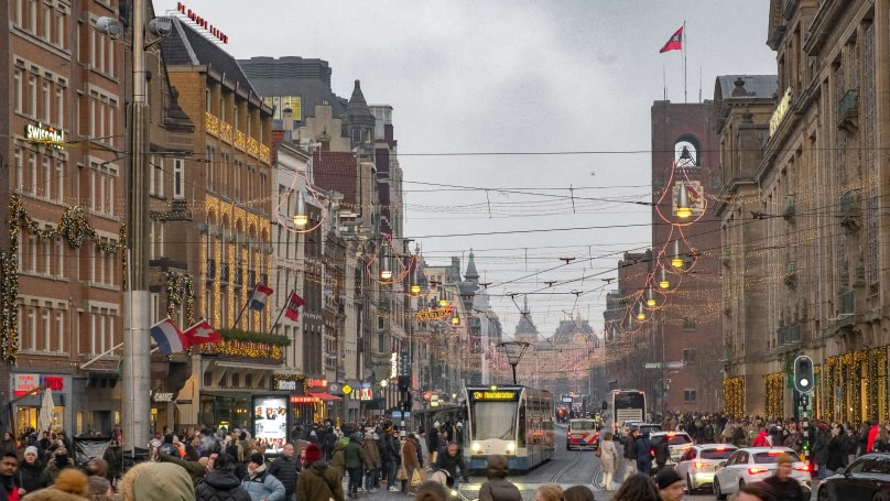 une photo d'un principal quartier commerçant animé d'Amsterdam avec des lumières et des décorations de Noël