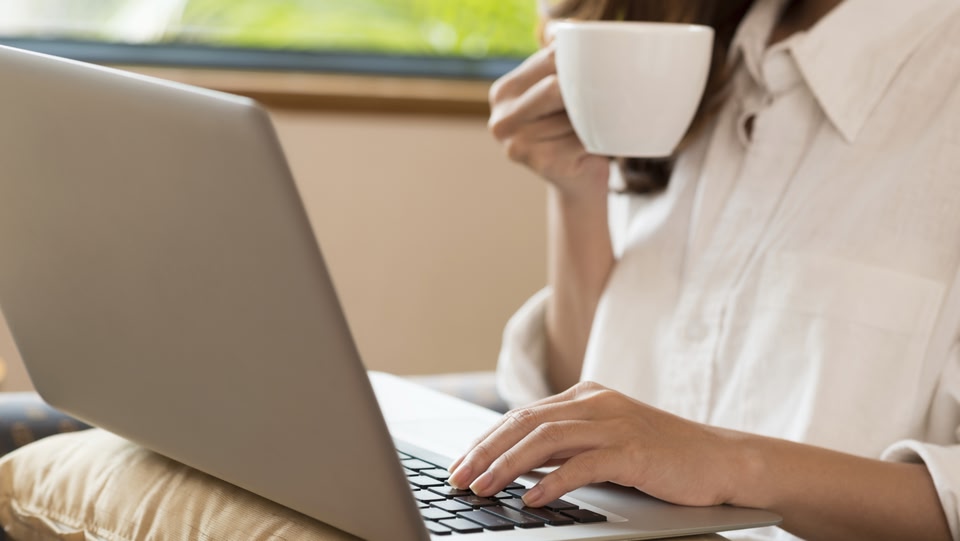 une femme assise avec son ordinateur portable ouvert s'assit en buvant un café