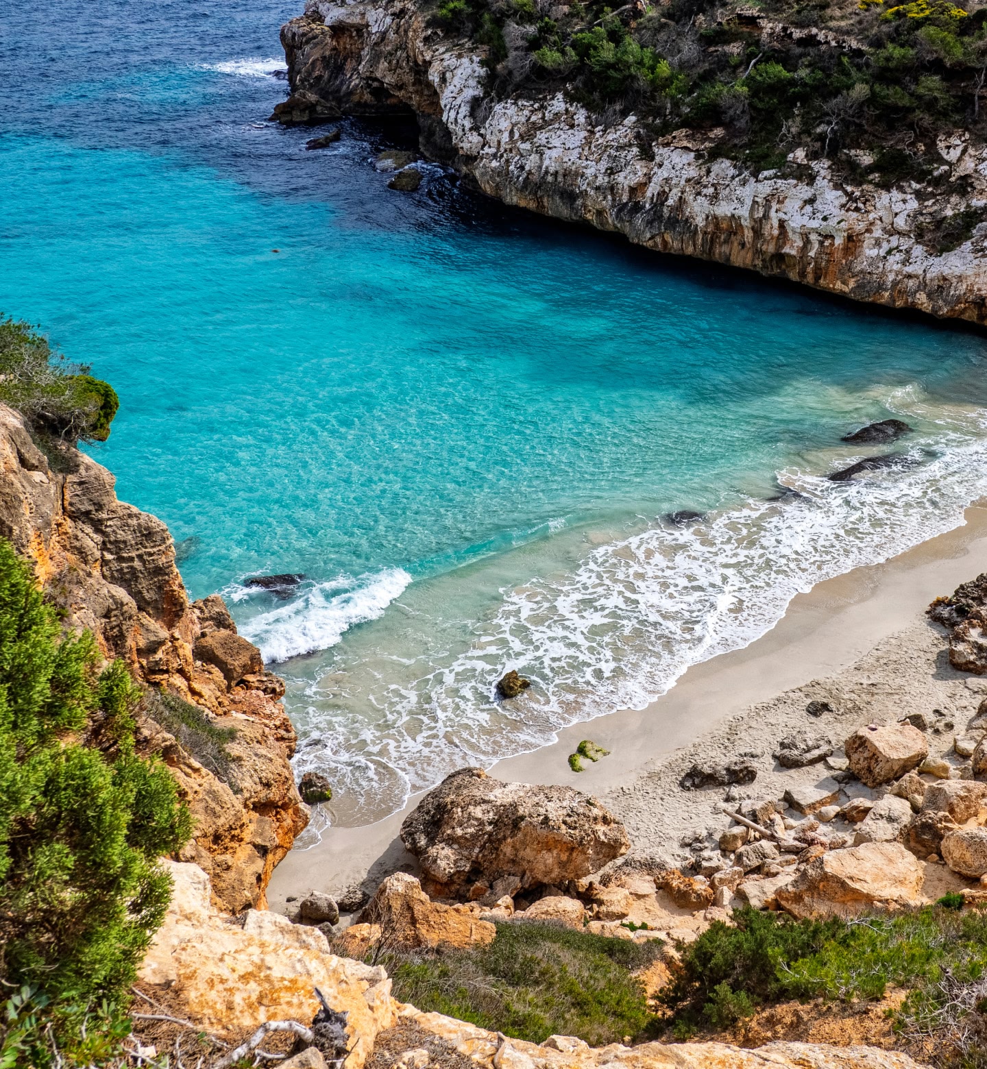 스페인 팔마 인근, 암벽이 있는 작은 만에 있는 모래 해변에 밀려드는 에메랄드빛 바다