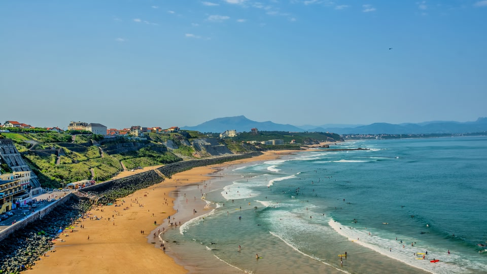 Vista costiera di una spiaggia con persone che si godono l'acqua e la sabbia.