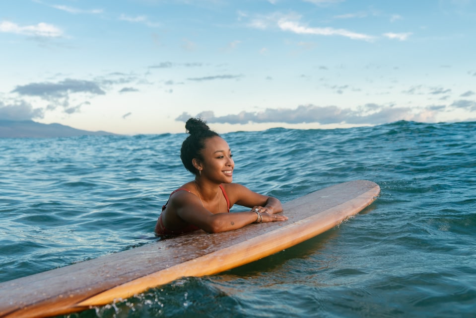 Woman leaning on a paddleboard in the water.
