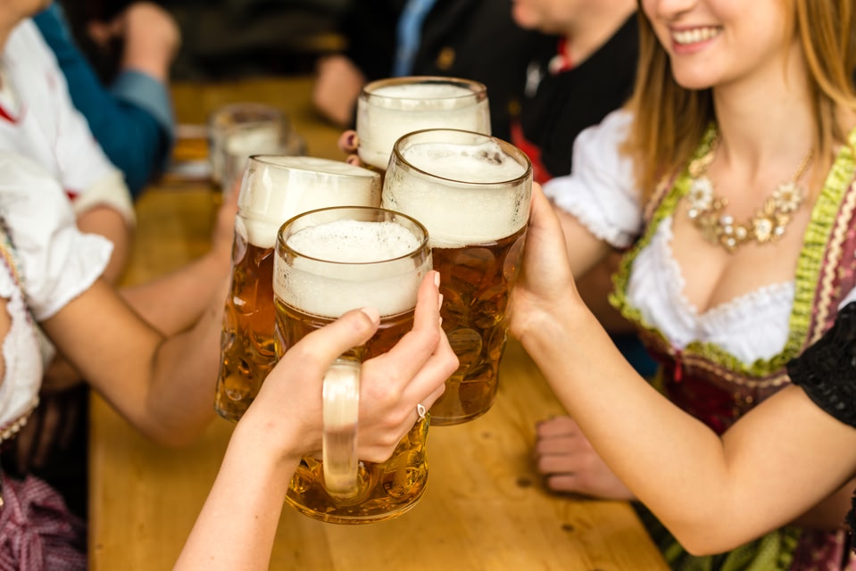 Several people doing a cheers with mugs full of beer
