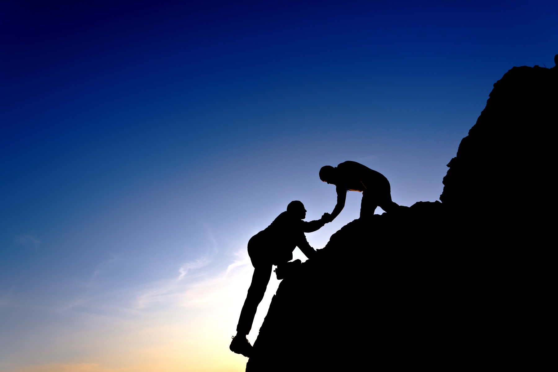 man helping other man up mountain