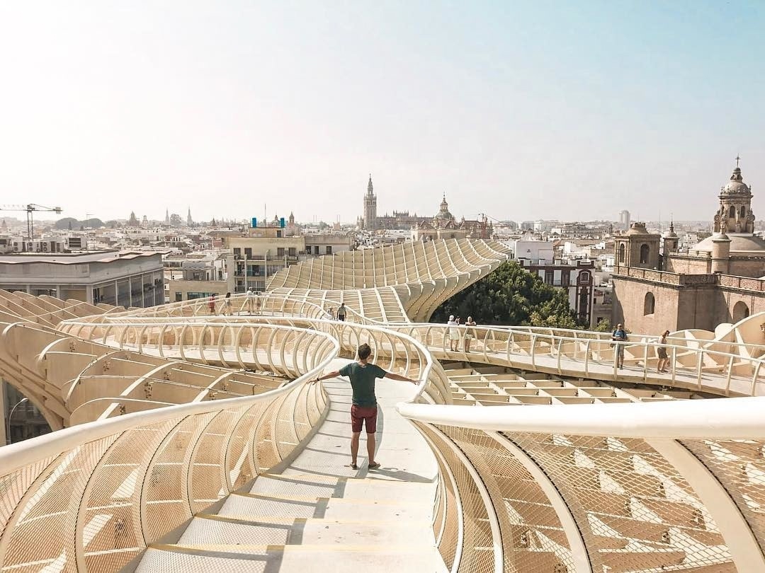 Travelers walking atop the modernist structure Setas de Sevilla enjoying views of the city.