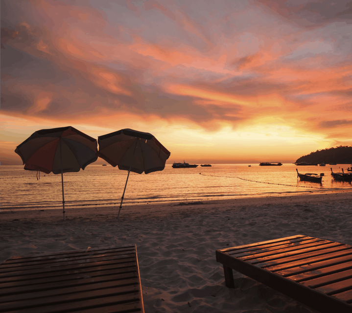 A sunset over Baga Beach in Goa with two parasols in the foreground