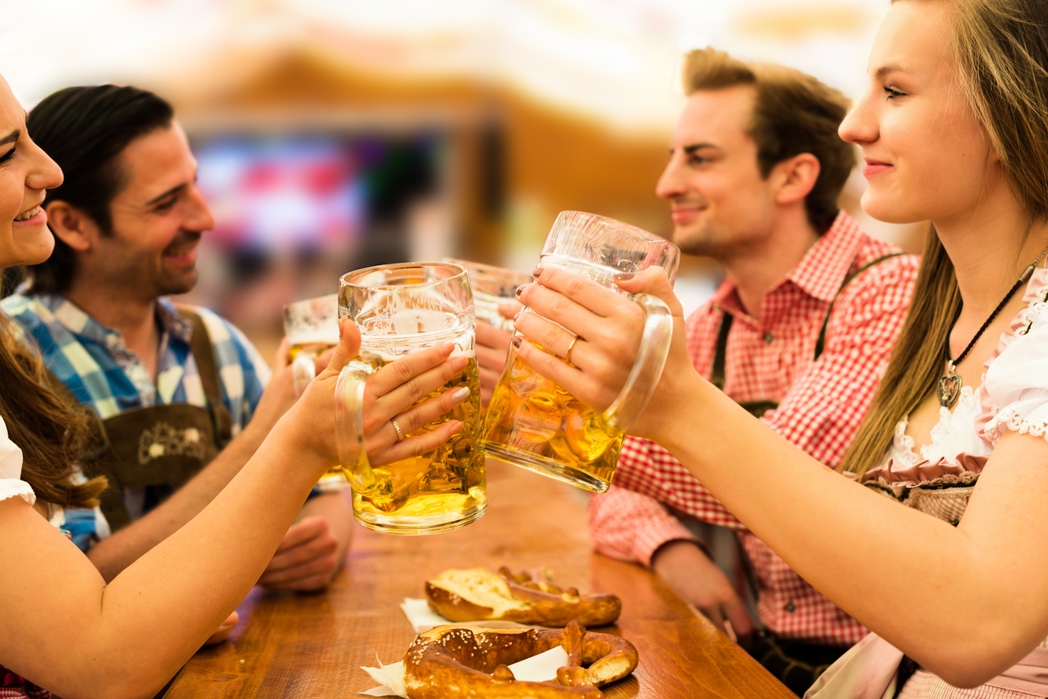 Girls in traditional Dirndl dresses are drinking beer and having fun with their friends at the Oktoberfest in Munich