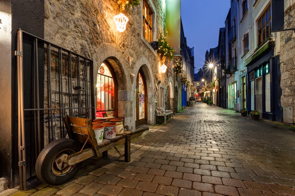 Cobbled street in Galway at dusk, with twinkling fairy lights.