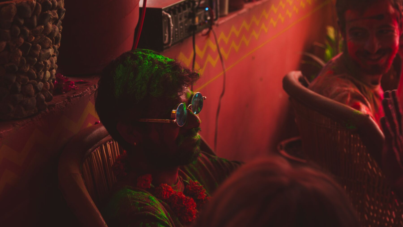 A man with funky glasses sat down at a music event.