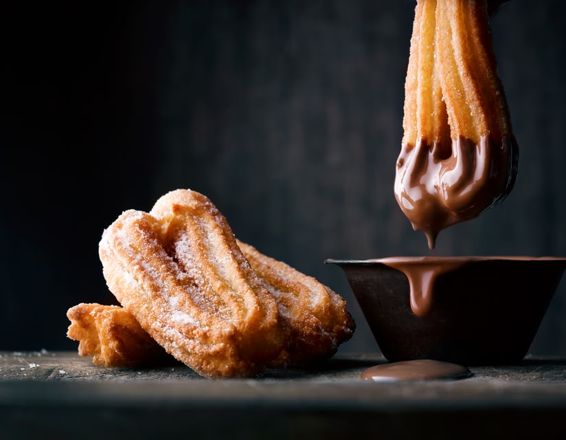 Churros being dipped in chocolate sauce - merienda time in Malaga