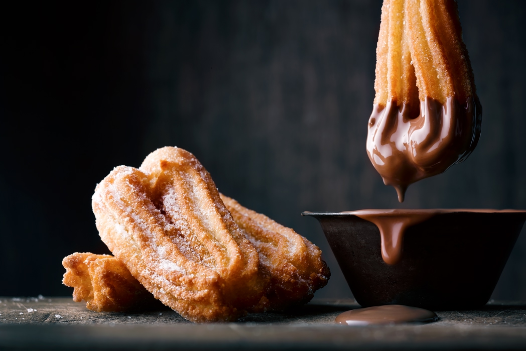 Churros being dipped in chocolate sauce - merienda time in Malaga