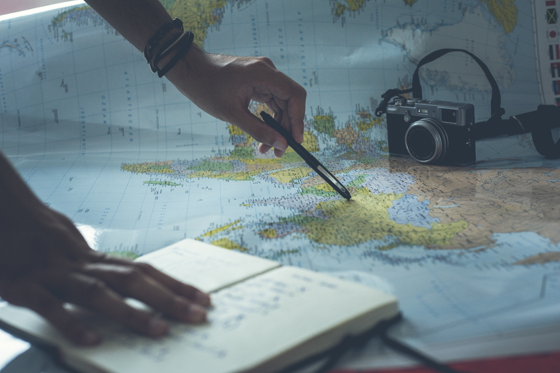 Pair of hands studying the world map and taking notes of tips for booking with confidence
