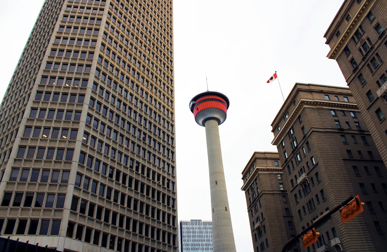 street view of Calgary Tower, lit up in red. Downtown Calgary.