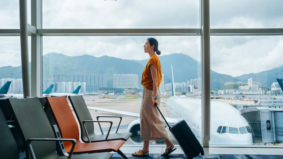 a women walking in an airport pulling a hand luggage case behind her 