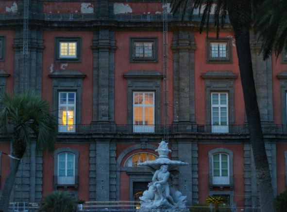 An image of a red building with a fountain in front