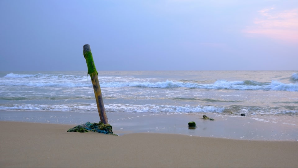 a pole sticking out of the sand on a beach