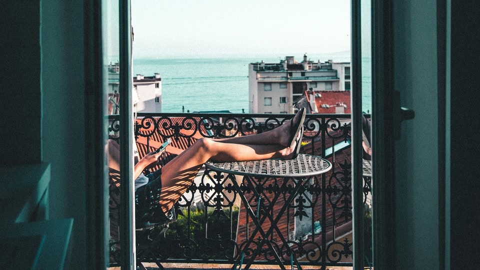 Persona che si rilassa su un balcone con i piedi sollevati, godendosi una vista panoramica sul mare