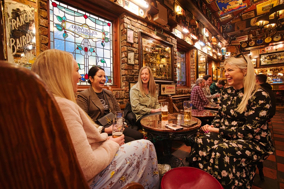 Group of young women chatting and laughing in a traditional Irish pub