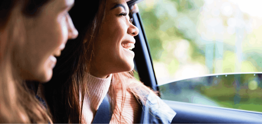 Two women in a car on their way to Mount Fuji laughing as they look out the window