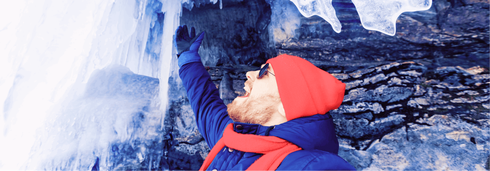 A man in an ice cave cheering while next to a wall of ice