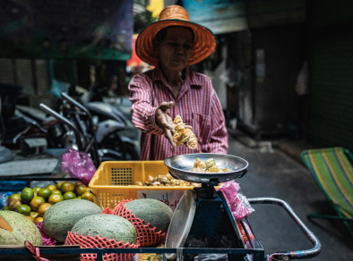 Eine fesselnde Aufnahme eines geschäftigen Straßenmarktes in Krabi mit einer geschickten Frau, die köstliches Essen über offener Flamme kocht.