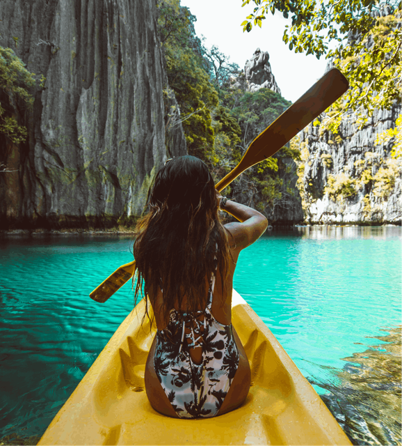 A woman paddles a canoe through vibrant blue waters