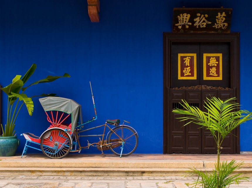 Chinese historic blue-walled building with trishaw outside