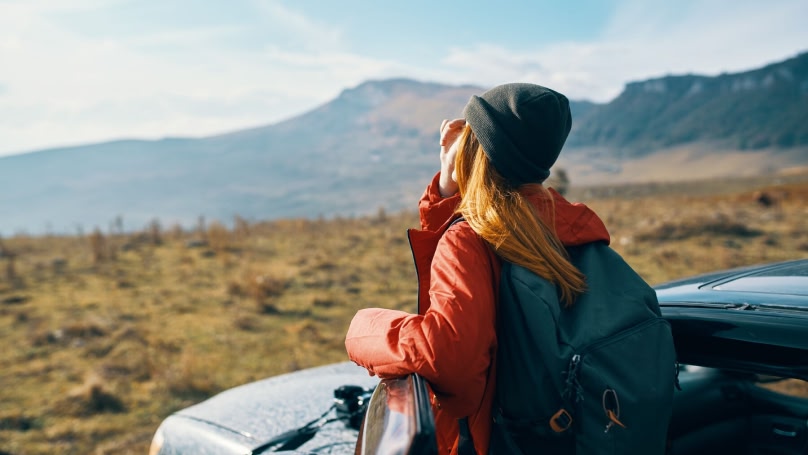Woman admiring view of park next to her parked car